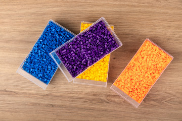 Fusible beads in plastic containers on a wooden table
