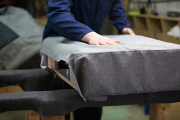 Closeup of a young man in a furniture factory who puts together one part of the sofa