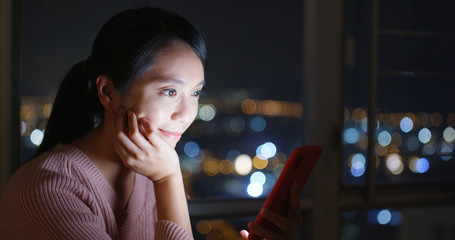 Woman look at mobile phone at night inside living room