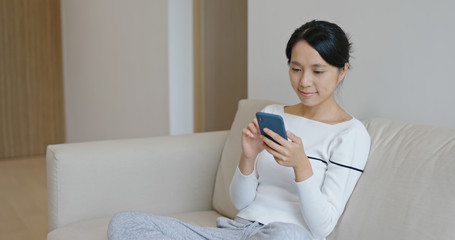 Woman look at mobile phone and sit on sofa