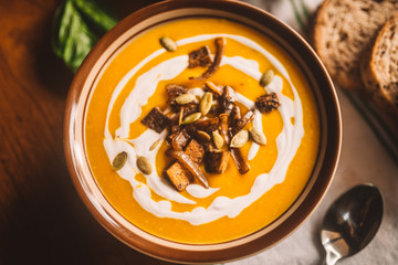  tasty autumn coconut pumpkin cream soup bowl with tofu, caramelized onion and seeds