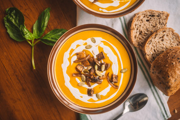  tasty autumn coconut pumpkin cream soup bowl with tofu, caramelized onion and seeds
