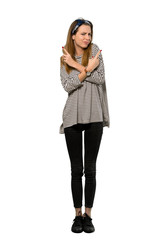 A full-length shot of a Young woman with headscarf pointing to the laterals having doubts over isolated white background