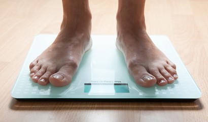 The legs of a young woman on the scales. Weight check. The concept of losing weight.