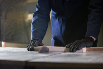 Close up of a young man in a furniture factory cutting the wooden pieces for the sofa