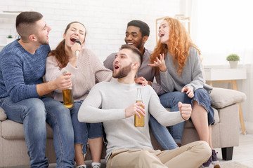 Group of friends playing karaoke and drinking beer
