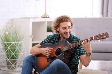 Young man playing acoustic guitar in living room