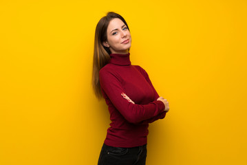 Obraz premium Woman with turtleneck over yellow wall with arms crossed and looking forward
