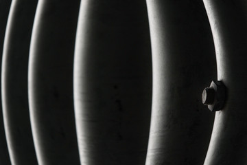 abstract detail with curved dark and bright lines, and with one bolt and nut; metal waves