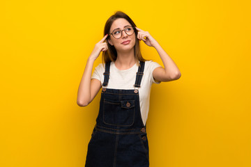 Woman over yellow wall having doubts and thinking