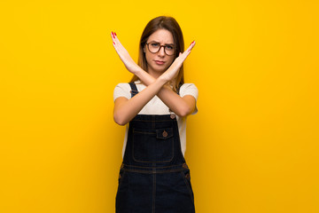 Woman over yellow wall making NO gesture