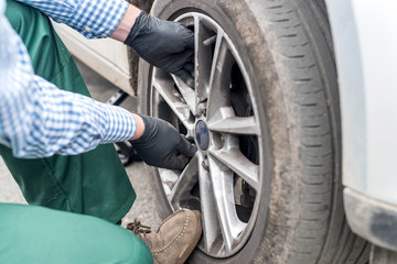 Naklejka premium Wheel of a car and worker hands fixing it