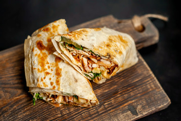 Burrito wraps with chicken and vegetables on a cutting board, against a background of concrete, Mexican shawarma