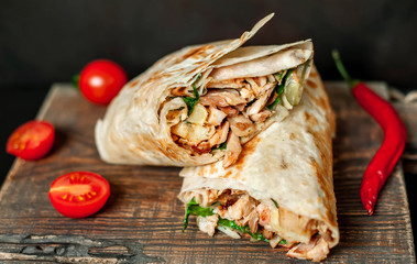 Burrito wraps with chicken and vegetables on a cutting board, against a background of concrete, Mexican shawarma