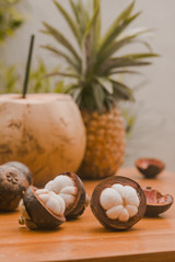 stiil life with exotic fruits mangosteen, coconut and pineapple on the wood table in tropical garden in Bali