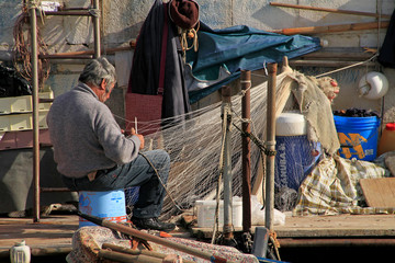 Fisherman repairing his net in the afternoon hours