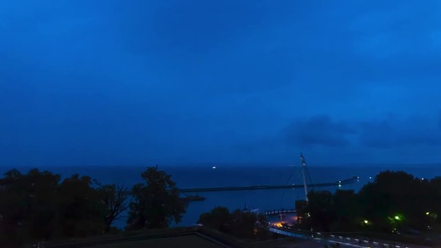 Sonnenuntergang am Hafen in Sassnitz auf der Insel R&uuml;gen - Blick auf den Himmel durch B&auml;ume auf das Wasser der Ostsee