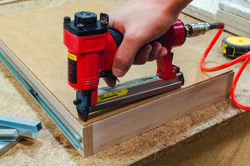 Red pneumatic stapler nails the bottom to the drawer - Powered by Adobe