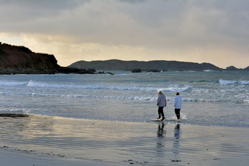 Deux femmes qui marchent dans l'eau sur une plage de Bretagne
