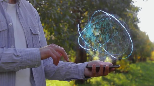 Unrecognizable man shows conceptual hologram with text E-ticket. Farmer on the background of the apple orchard in casual clothes with the technology of the future mobile screen