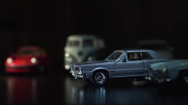  Vintage gray car on the background of toy cars. A ray of light creates the sunrise effect on the cars.