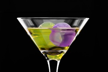 wine glass with colored ice cubes on black background