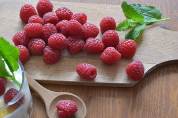 raspberries on a wooden cutting board on a wooden table with a wooden spoon