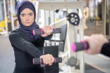 healthy muslim woman with hijab exercising in gym