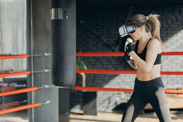 Attractive woman boxing in VR 360 headset training for kicking in virtual reality