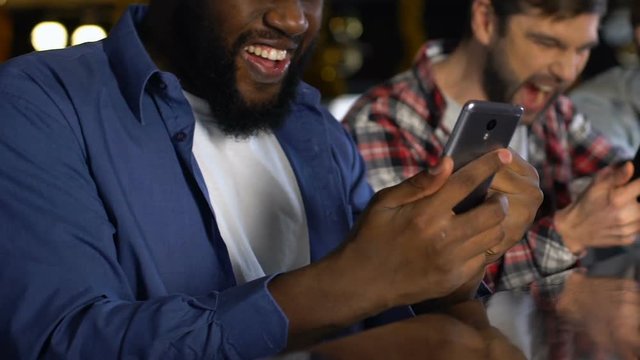 Male friends with smartphones excited about favorite team victory, checking bets