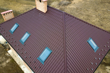 Aerial top view of building steep brown shingle roof, brick chimneys and small attic windows on...