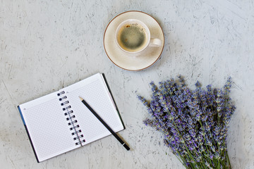 Morning coffee mug, blank notepad and purple lavender flowers on gray background, cozy summer breakfast, top view, flat lay