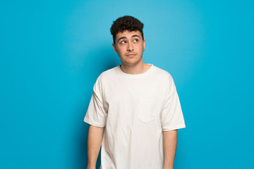 Young man over blue background looking up with serious face