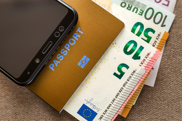 Modern black cellphone, Euro money banknotes bills and travel passport on copy space background. Travelling light, comfortable journey concept.