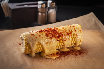 grilled corn with cheese sauce on a wooden board, close-up