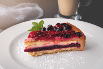 slice of cheesecake with berry jelly and mint on a white plate, close-up