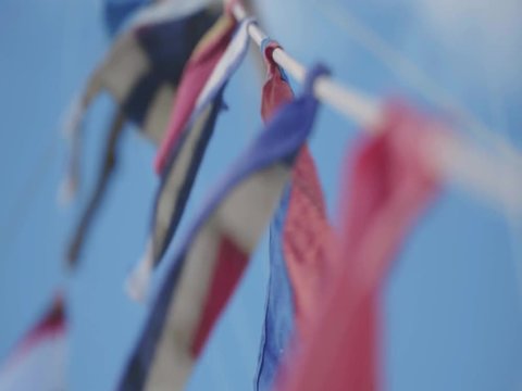 Rope with many small flags flutter on wind. Soft clouds at sky