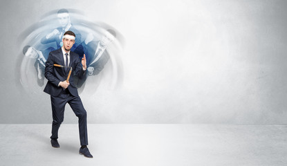 Fototapeta premium Young businessman in suit fighting with empty wall background 