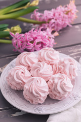 Traditional Russian homemade merengue marshmallow or zephyr on a plate with pink hyacinth on wooden background