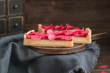 Homemade strawberry tart sliced on wooden plate on the rustic background