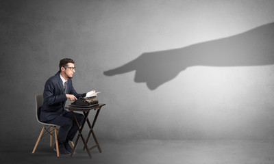 Shadow hand pointing at a small afraid worker
