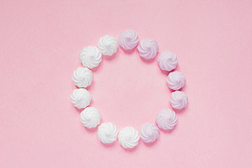 Top view of white and pink twisted meringues  on pink background. French dessert prepared from whipped with sugar and baked egg whites. Greeting card with copy space