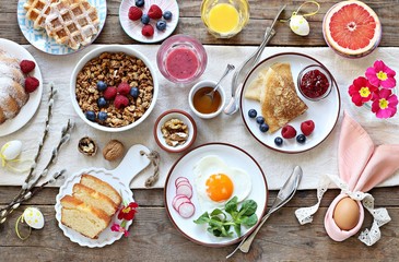 Easter festive breakfast or brunch set served on rustic wooden table. Overhead view, copy space