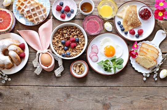 Easter festive breakfast or brunch set served on rustic wooden table. Overhead view, copy space