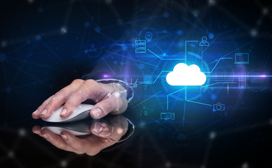 Hand using wireless mouse in a dark environment with cloud technology and online storage concept