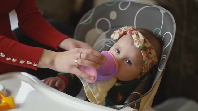 the little girl is drinking from the trough