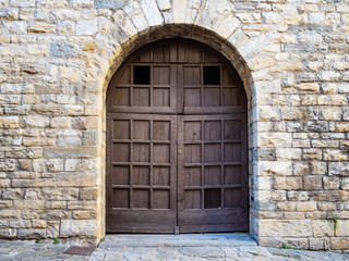 Fototapeta na wymiar wide outdoor wooden door in stone medieval house