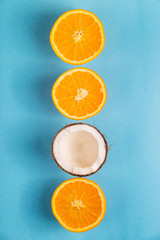 Juicy ripe oranges and open coconut on a bright blue background. Summer Food Concept. Top view, flat lay