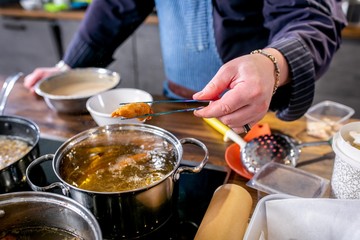 Fototapeta premium Chef pulls out fried fish pieces in batter. Master class in the kitchen. The process of cooking. Step by step. Tutorial. Close-up
