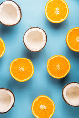 Juicy ripe orange halves and white open coconut on a bright blue background pattern. Summer Food Concept. Background, top view, flat lay
